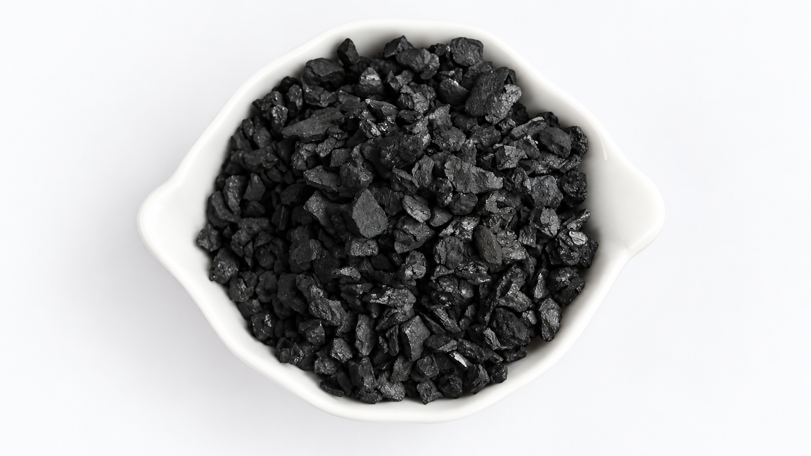 Black coal-based activated carbon granules in a white bowl